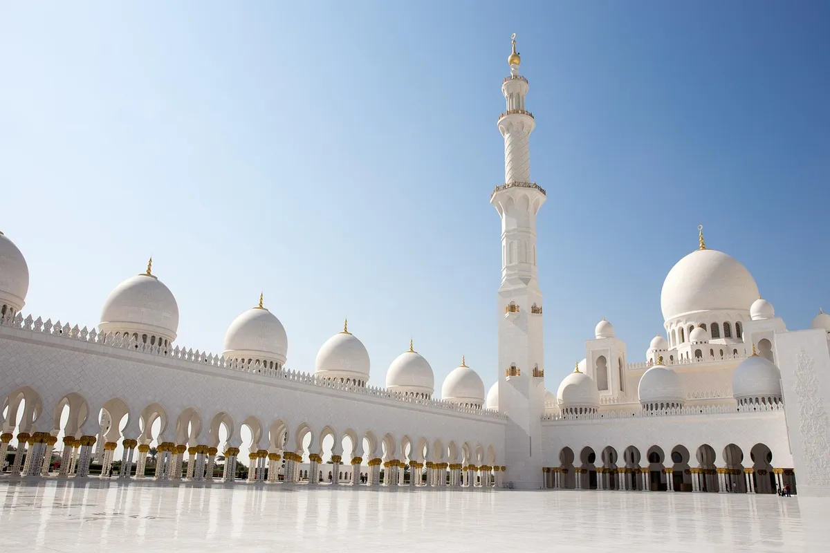 Coupoles et minaret blancs de la grande mosquée Cheikh Zayed sous un ciel bleu, à Abou Dabi